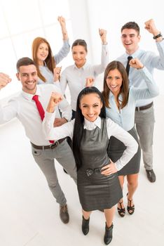 Group of young successful business people standing proudly with fist up and looking at camera.