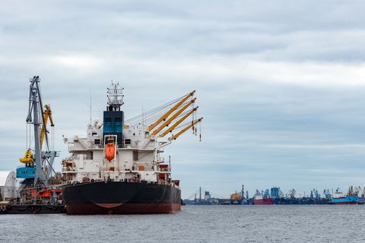 Black cargo ship loading in the port of Riga, Europe