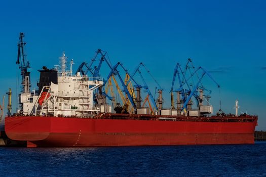 Red cargo ship loading in the port of Riga, Europe
