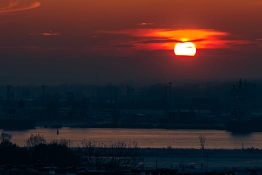 Hot orange sunset over the river. Urban landscape