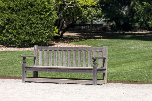 This photo was taken at a formal botanical garden near San Francisco, California. Spring had arrived, and flowers are in bloom. This image features an old comfortable bench in a formal garden.