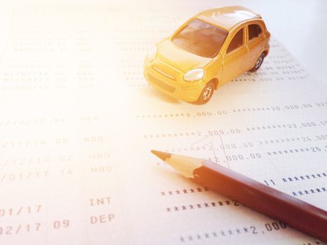 Business, finance, savings, banking or car loan concept : Miniature car model, pencil and savings account passbook or financial statement on white background