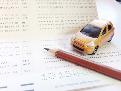 Business, finance, savings, banking or car loan concept : Miniature car model, pencil and savings account passbook or financial statement on white background