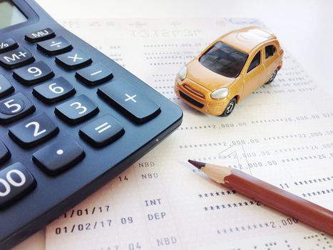 Business, finance, savings, banking or car loan concept : Miniature car model, pencil, calculator and savings account passbook or financial statement on white background