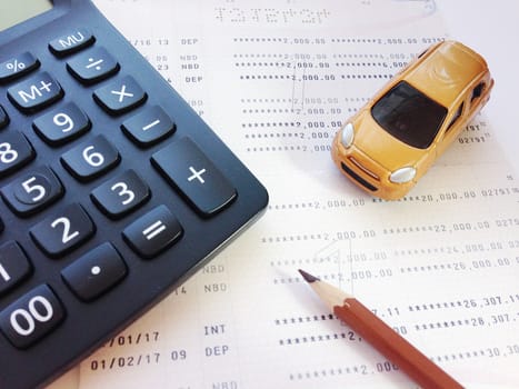 Business, finance, savings, banking or car loan concept : Miniature car model, pencil, calculator and savings account passbook or financial statement on white background