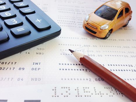 Business, finance, savings, banking or car loan concept : Miniature car model, pencil, calculator and savings account passbook or financial statement on white background