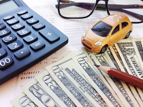 Business, finance, savings, banking or car loan concept : Miniature car model, pencil, money, calculator, eyeglasses and savings account passbook or financial statement on white background