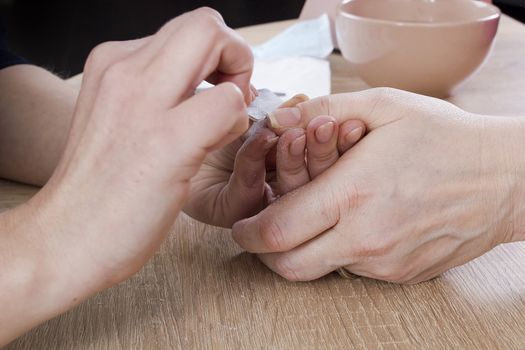 Professional manicure procedure in beauty salon. Hands close up.