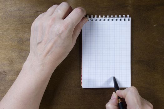 Hand writing on empty notepad on a wooden table