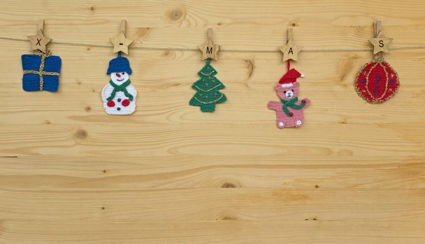 Several crocheted christmas hangers on a cord on wood and text x-mas, background