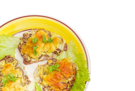 Fragment of the dish with several pork chops baked with onion, mushrooms and cheese and decorated with parsley and lettuce leaves on a light background
