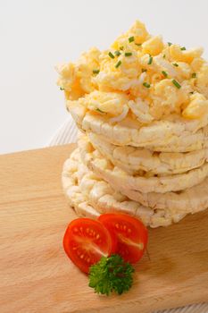 slices of puffed rice bread with scrambled eggs on wooden cutting board