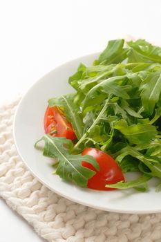 plate of arugula and tomato salad on white table mat