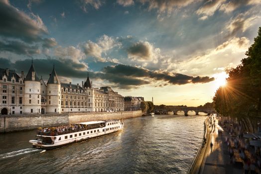 Consiergerie, Pont Neuf and Seine river with tour boat at sunny summer sunset, Paris, France