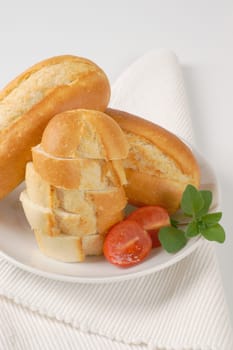 whole and sliced mini baguettes on white plate