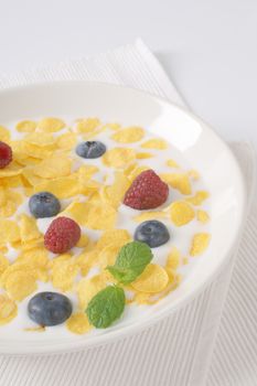 plate of corn flakes with milk and fresh berry fruit