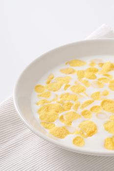 plate of corn flakes with fresh milk on white place mat