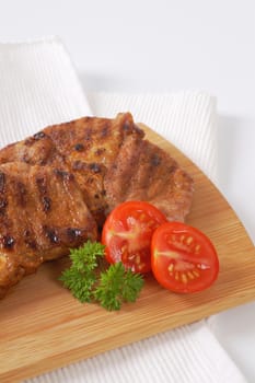two slices of grilled pork meat on wooden cutting board