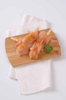 raw chicken skewers on wooden cutting board