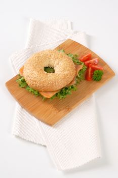 sesame bagel sandwich with smoked salmon on wooden cutting board