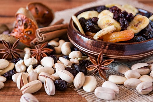 Mix of dried fruits in a wooden bowl and nuts over a rustic table