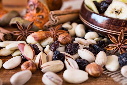 Closeup of mix of dried fruits in a wooden bowl and nuts over a rustic table