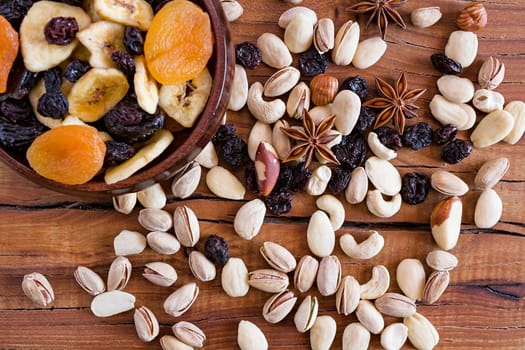 Closeup of mix of dried fruits in a wooden bowl and nuts seen from above