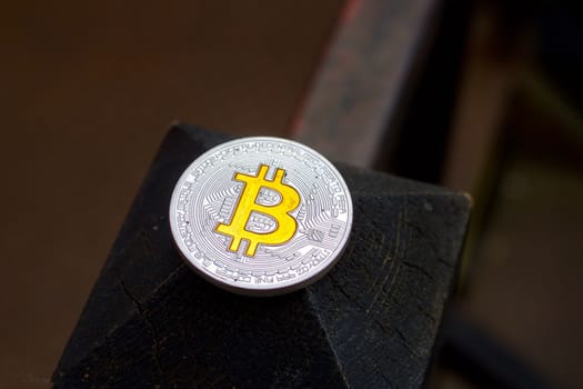 Cryptocurrency physical silver bitcoin coin with yellow sign on the wood.