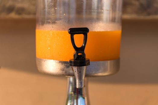 Orange juice in water cooler for breakfast at the hotel.