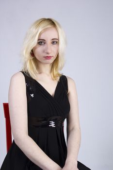 Portrait of a young sad blonde woman on a gray background