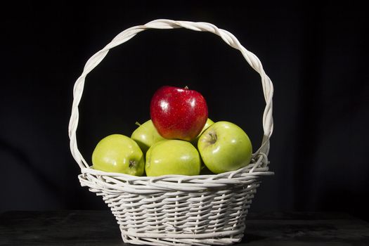 Ripe apples in a wicker basket on a black background