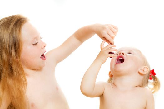 two little girls eat sweet cherry on the isolated background