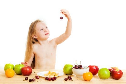the little girl is fruit at a table on the isolated background