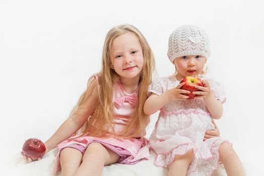 two little girls sit on the isolated background