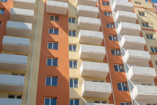 kind of a new multistorey brick residential building with balconies on a sunny day