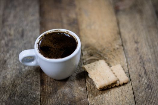 Freshly brewed coffee in mugs on a wooden table with a mill on a black background