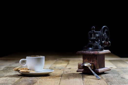 Freshly brewed coffee in mugs on a wooden table with a mill on a black background