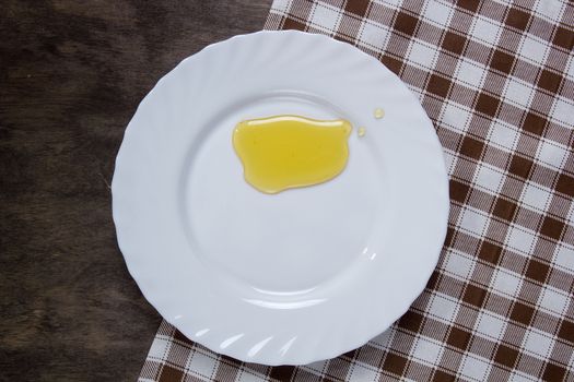 White plate with honey on a wooden table