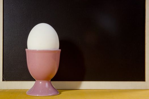 Cooked egg in a holder on a black board background