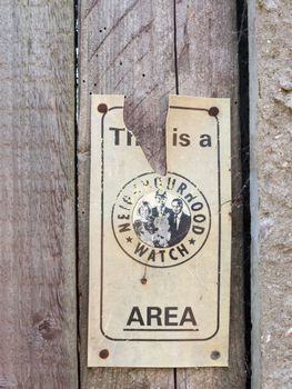 a broken neighborhood watch sign area outside on fence