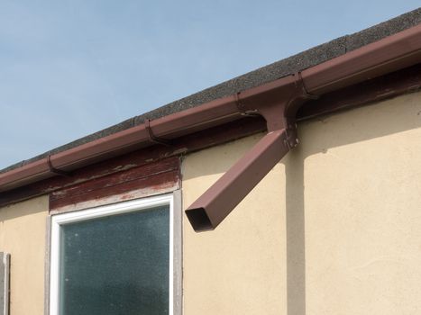a brown gutterpipe outside on the back of a house and garage