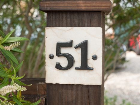 white house number plate 51 on post outside in garden