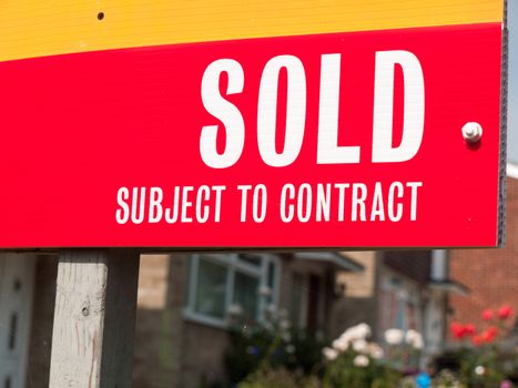red sold subject to contract sign outside in garden of house