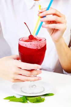 Cherry smoothie in a big glass cup with two straws in woman's hands. Lady with a drink