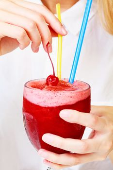 Closeup shot of cherry smoothie in a big glass cup with two straws in woman's hands. Lady with a drink