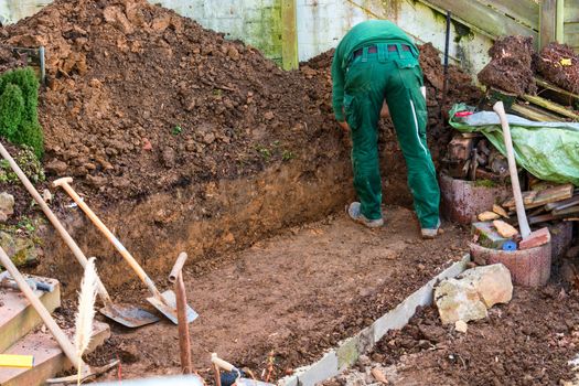 Man with dig of soil on a outdoor construction site.