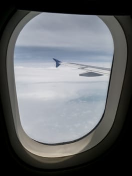 View of airplane wing and blue sky from airplane window.
