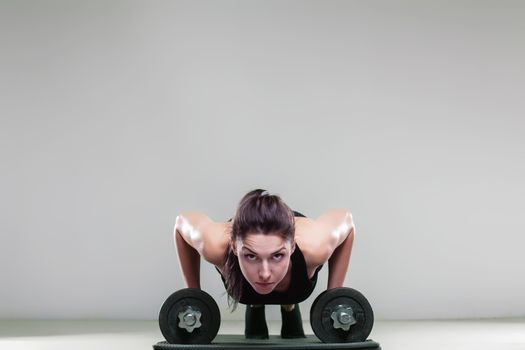 Fitness girl doing push ups with weights