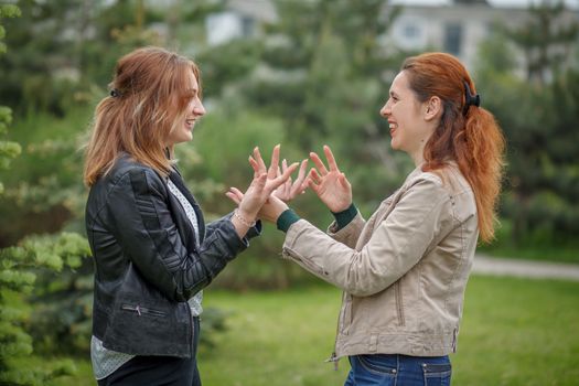 Two smiling women face to face having conversation gesticulate with hands