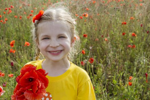 Smiling girl holding bouquet poppies among field